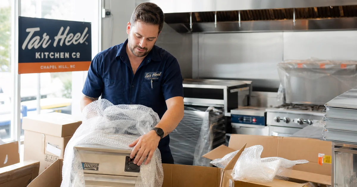 A new restaurant owner unboxing fresh commercial kitchen equipment in a North Carolina kitchen